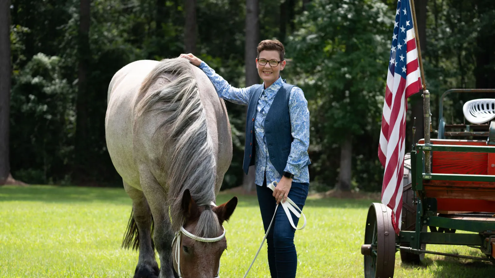 Stacy Pearsall and one of her horses smiling next to the American flag.